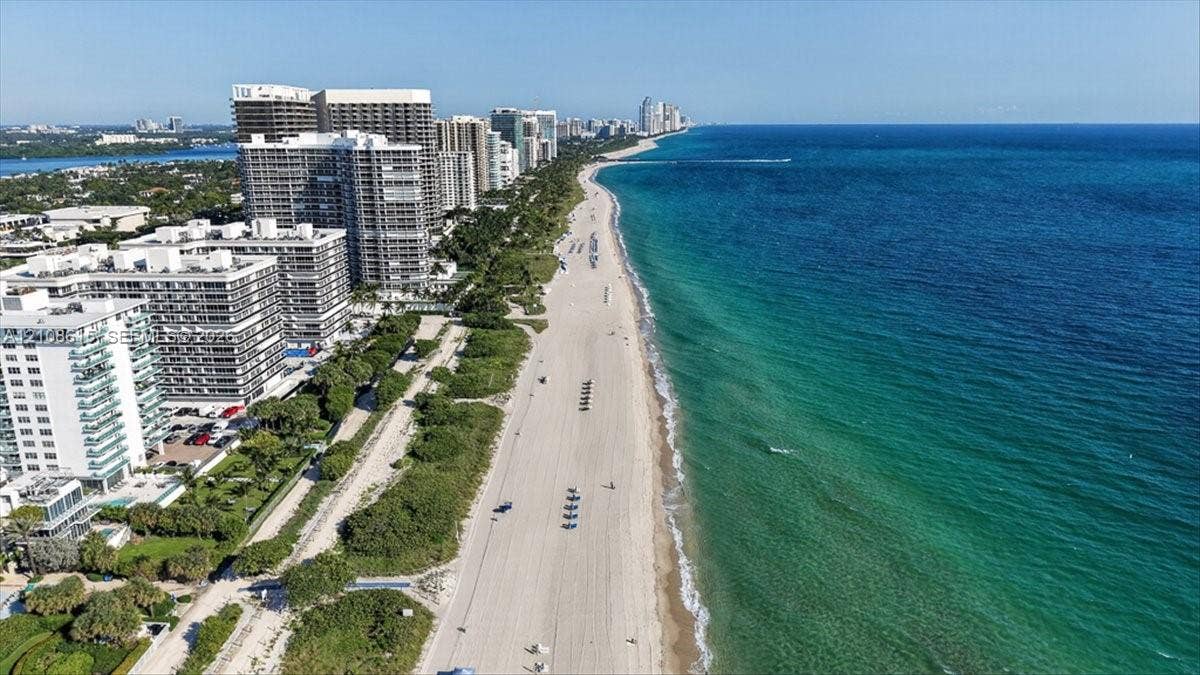 9455 Collins Avenue, #1201, Surfside, FL 33154 Aerial perspective of a coastal stretch featuring a sandy beach, turquoise ocean water, mature greenery, and multi-story structural developments