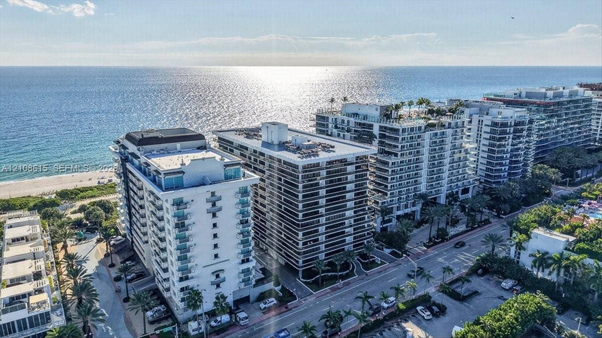 9455 Collins Avenue, #1201, Surfside, FL 33154 Aerial perspective of coastal high-rise building with glass-railed balconies, exterior masonry facade, and direct proximity to the oceanfront