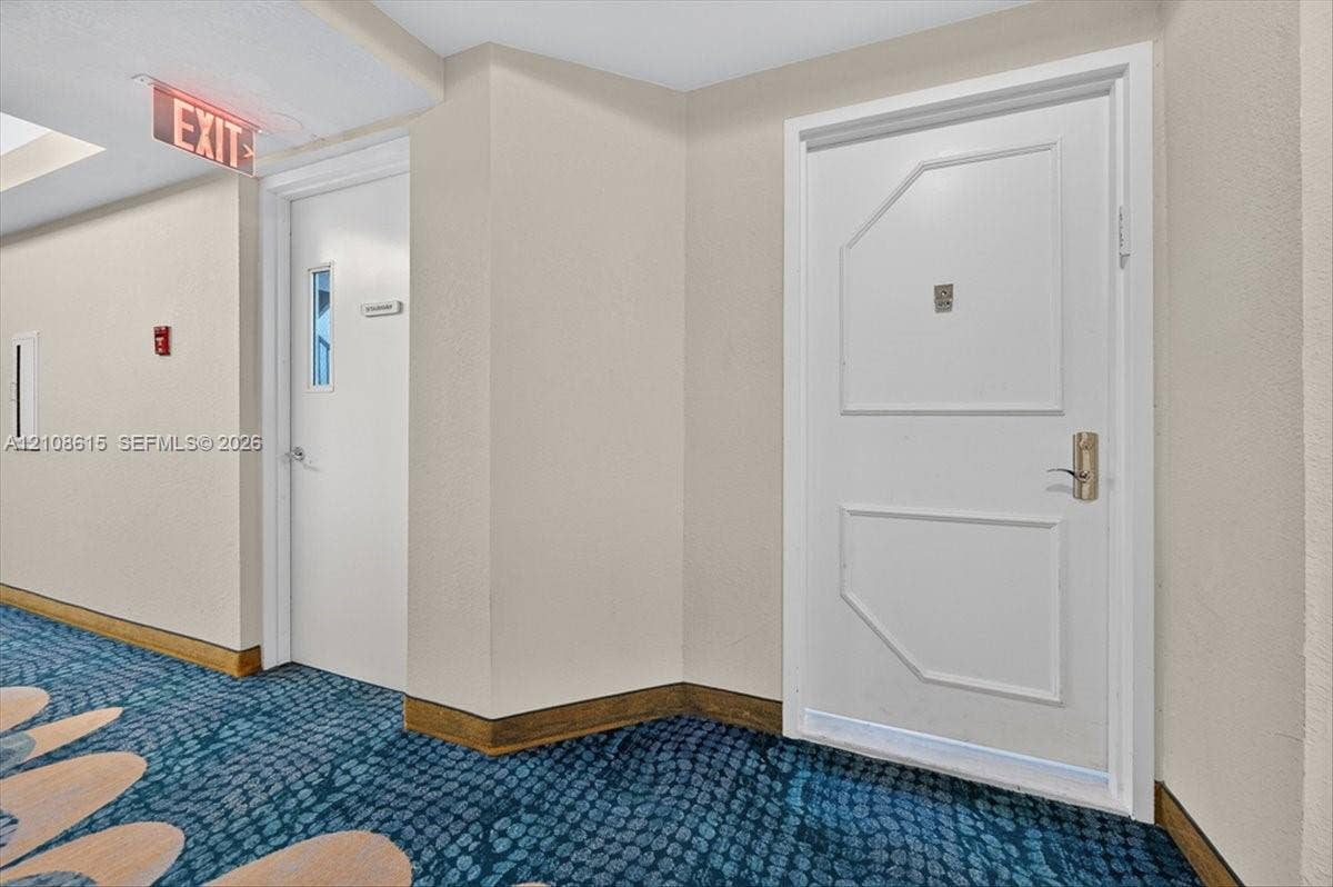 9455 Collins Avenue, #1201, Surfside, FL 33154 Interior hallway featuring patterned floor covering, smooth wall finishes, and solid-core entry doors with metallic lever hardware