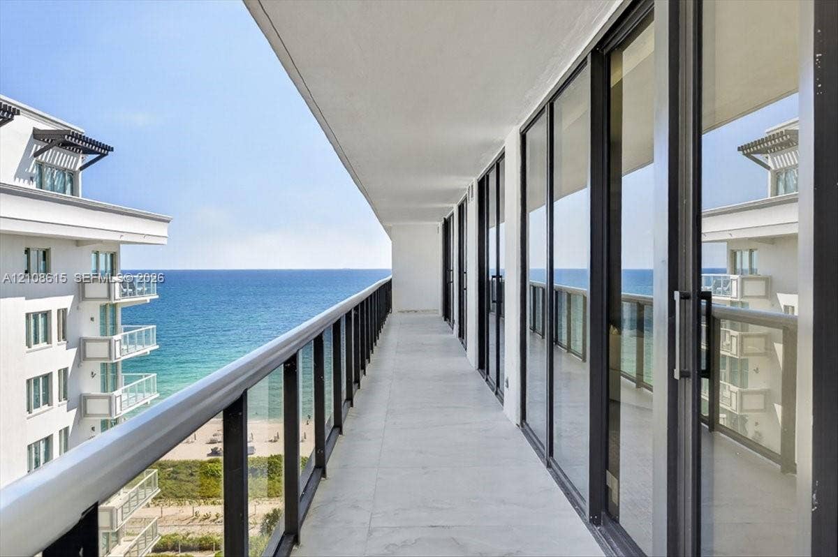 9455 Collins Avenue, #1201, Surfside, FL 33154 Expansive covered balcony featuring floor-to-ceiling glass doors, sleek metal railing, stone-finish flooring, and direct ocean exposure