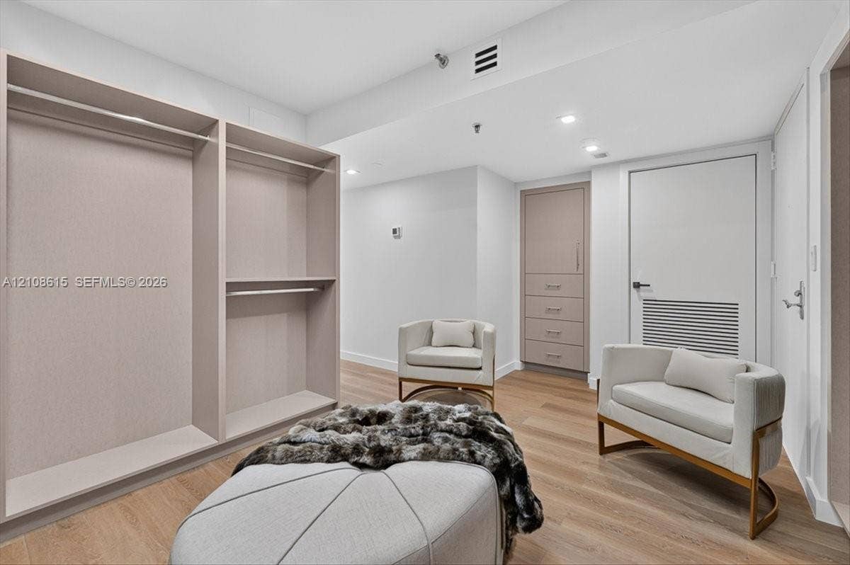 9455 Collins Avenue, #1201, Surfside, FL 33154 Custom dressing area featuring built-in cabinetry, floor-to-ceiling closet organization, recessed ceiling lighting, and wood-finish flooring