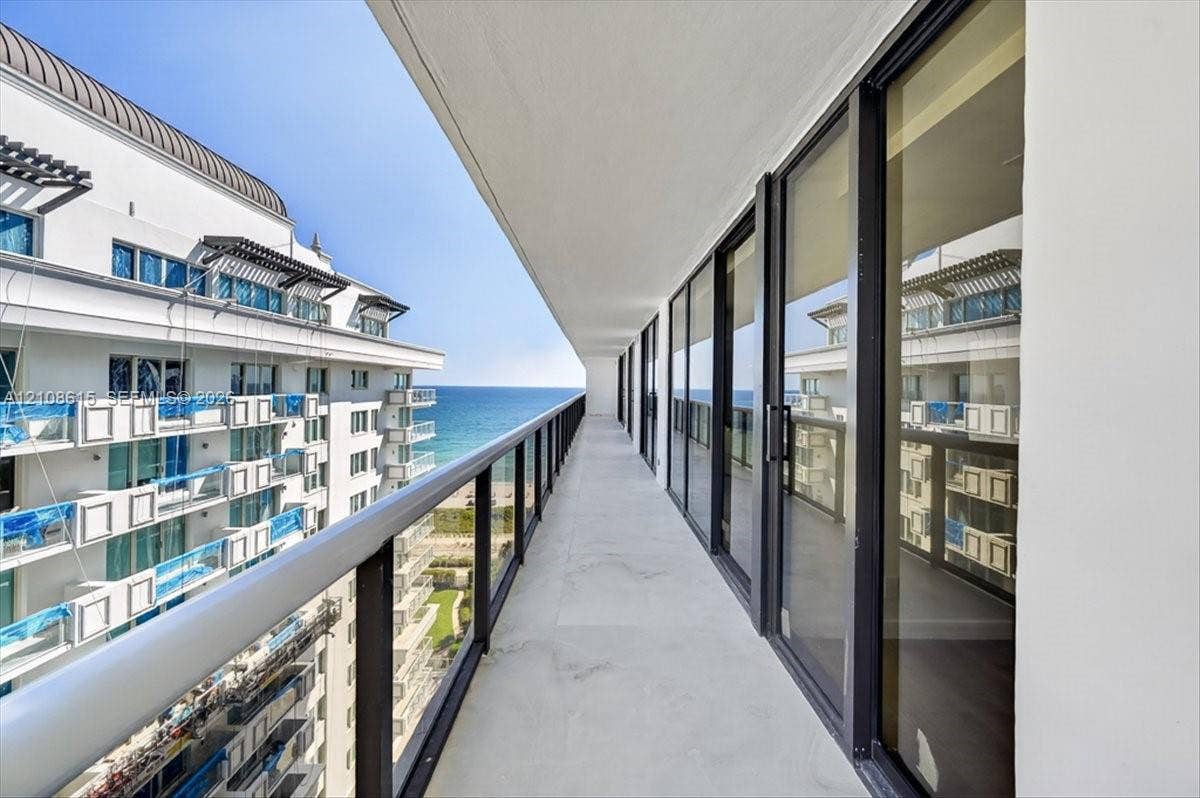 9455 Collins Avenue, #1201, Surfside, FL 33154 Expansive covered balcony featuring glass panel railings, concrete flooring, and full-height sliding glass doors