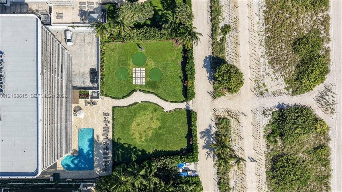 9455 Collins Avenue, #1201, Surfside, FL 33154 Aerial perspective of property grounds featuring an outdoor swimming pool, a putting green, paved walkways, and mature landscaping