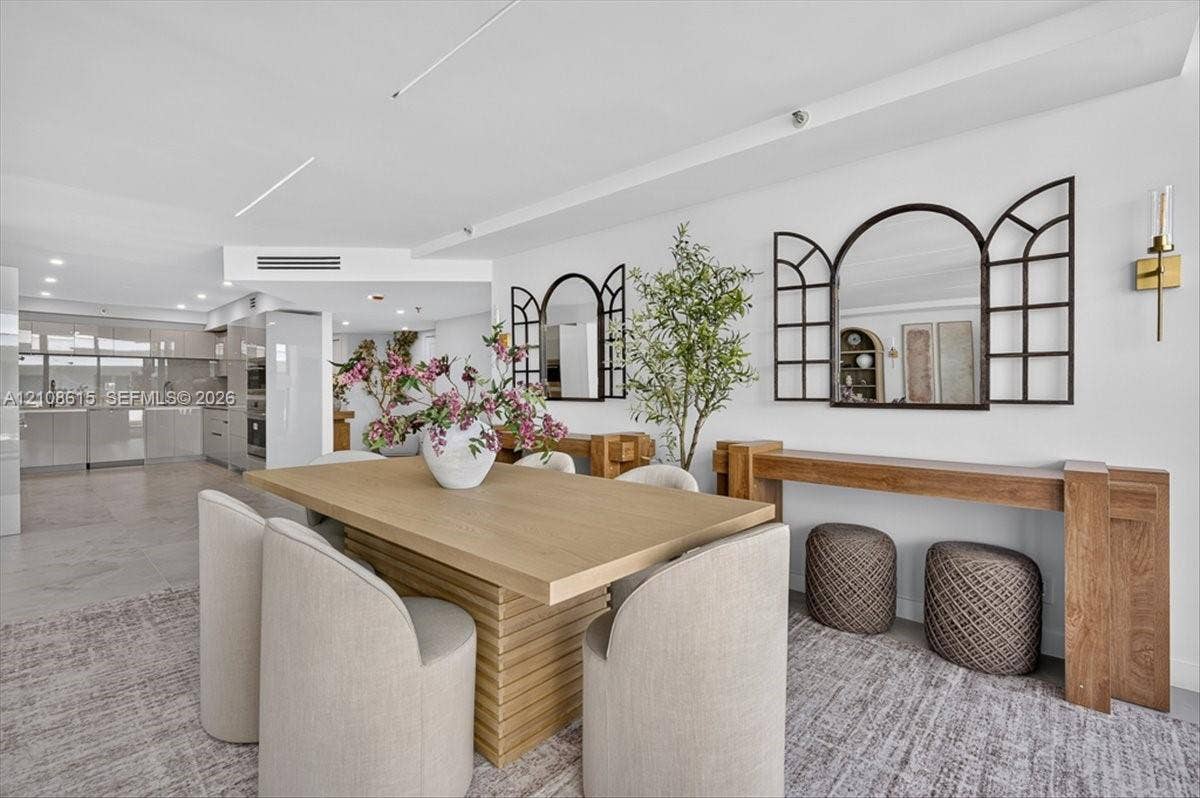 9455 Collins Avenue, #1201, Surfside, FL 33154 Open-concept interior featuring recessed lighting, sleek cabinetry, neutral tile flooring, and minimalist wall-mounted gold-toned light fixtures