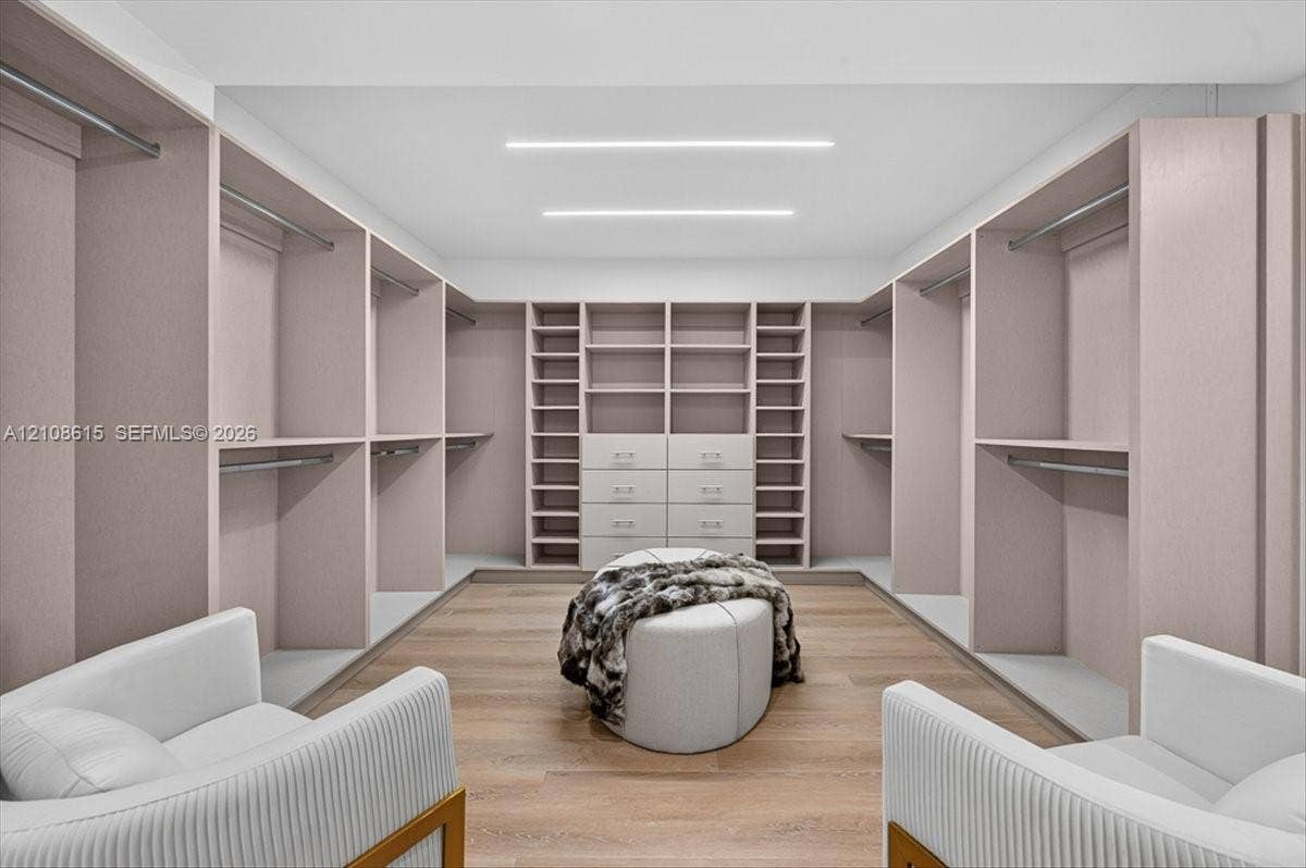 9455 Collins Avenue, #1201, Surfside, FL 33154 Custom walk-in closet featuring floor-to-ceiling built-in cabinetry, integrated drawer storage, wood-finish flooring, and recessed linear ceiling lighting