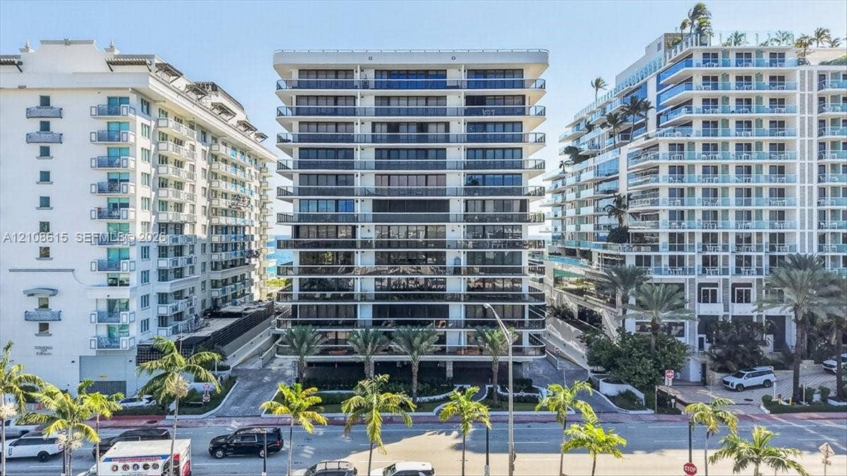 9455 Collins Avenue, #1201, Surfside, FL 33154 High-rise building exterior featuring tiered concrete balconies with glass railings, floor-to-ceiling windows, and mature palm trees