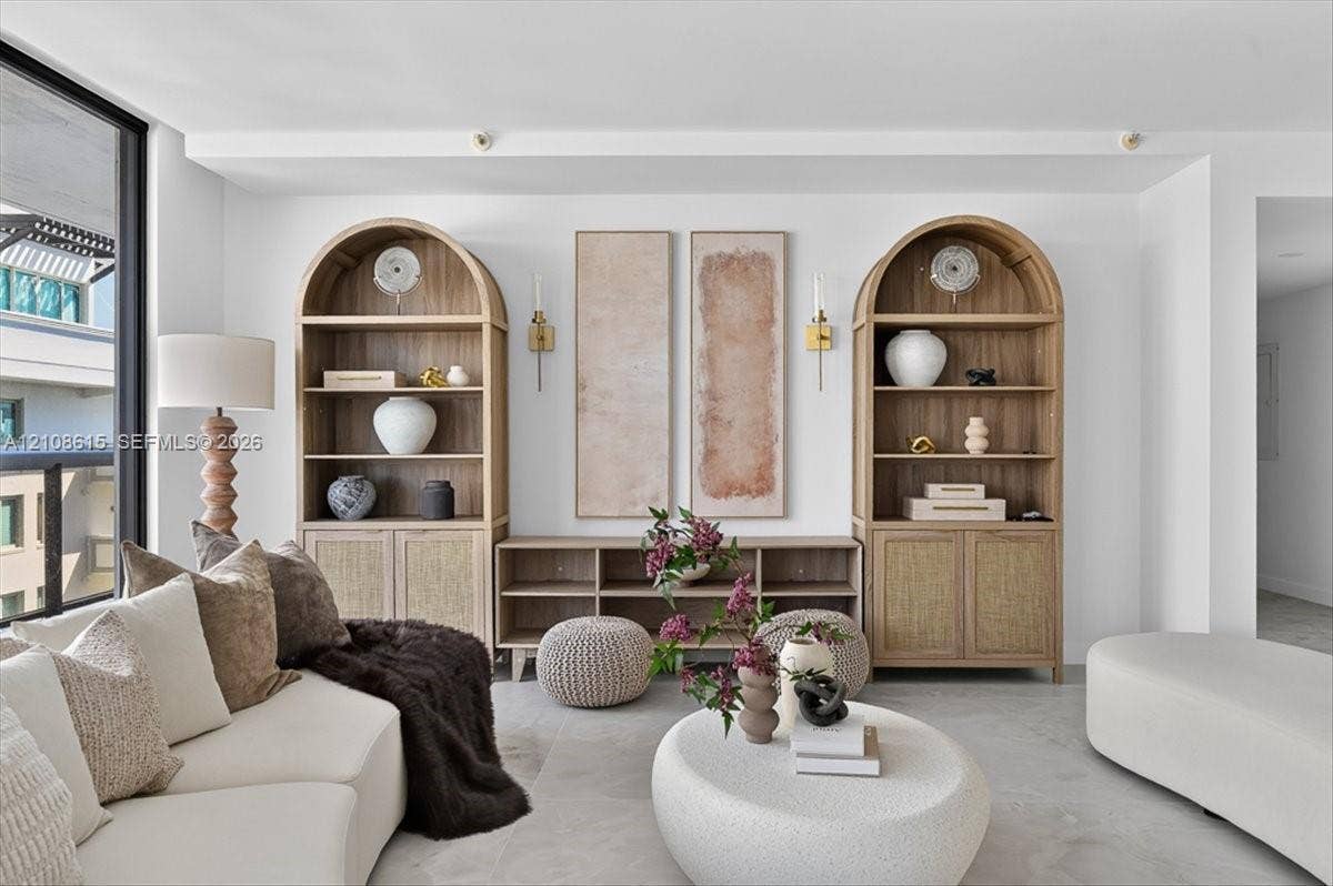 9455 Collins Avenue, #1201, Surfside, FL 33154 Custom built-in wood shelving units with arched tops, integrated lower cabinet storage, floor-to-ceiling glass window panel, and wall-mounted metallic sconces