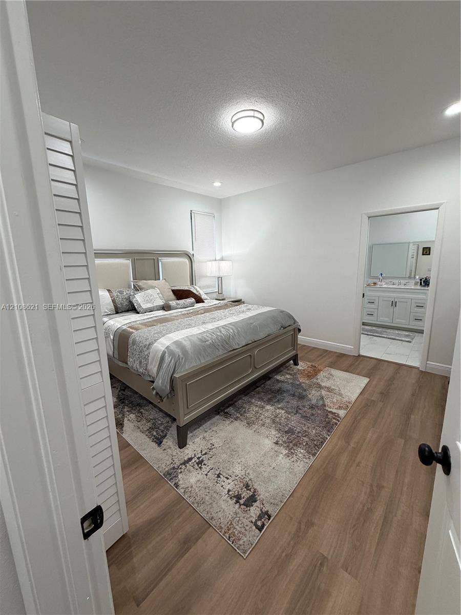 Neutral-toned interior featuring wood-finish flooring, louvered closet doors, and recessed lighting