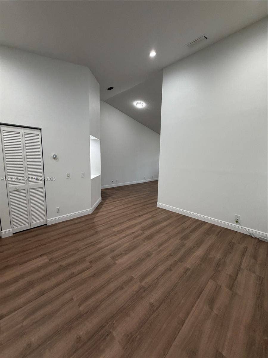 Interior space featuring vaulted ceilings, wood-finish flooring, recessed lighting, and a built-in wall niche with closet storage