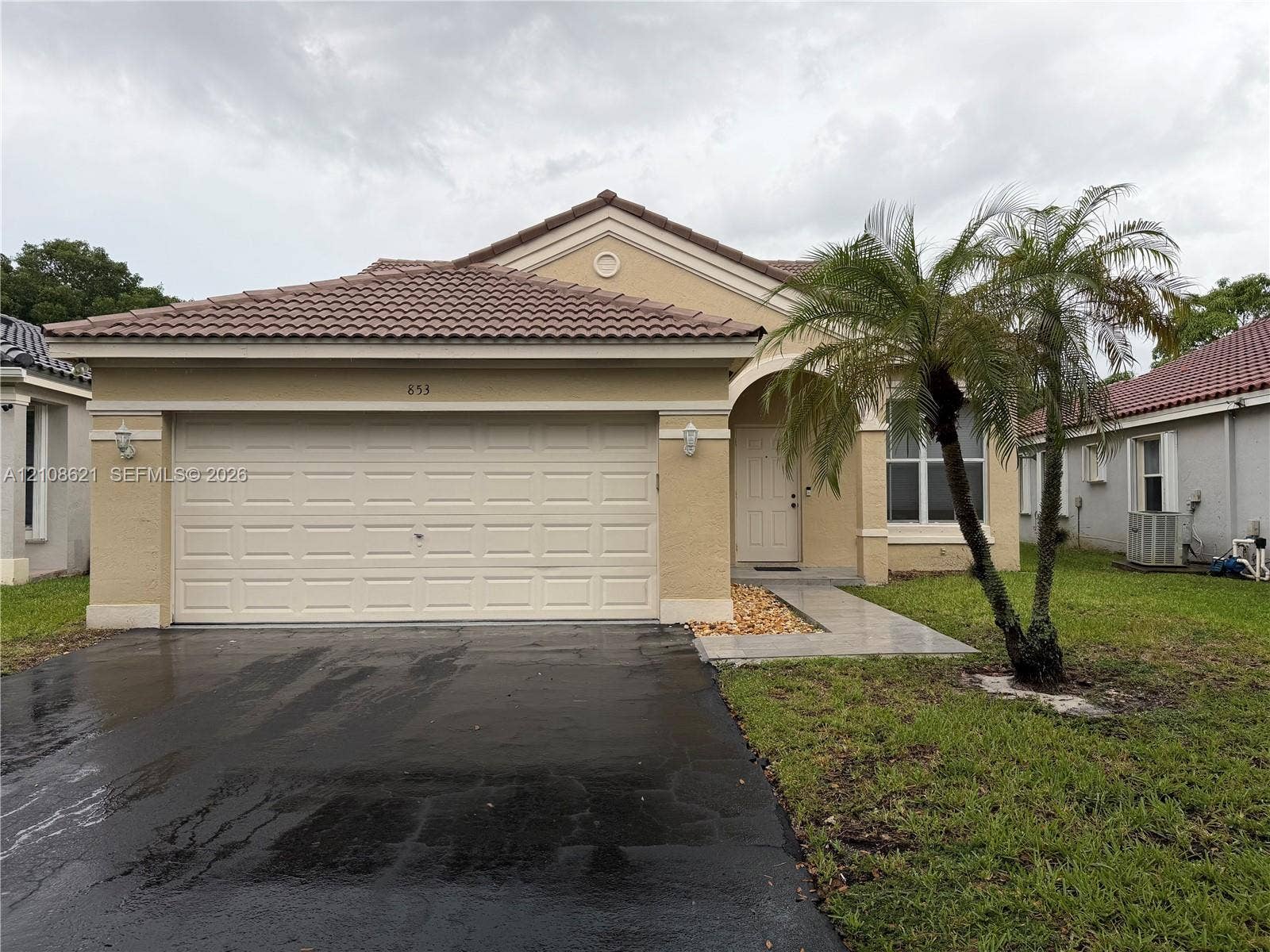 Stucco exterior featuring a tiled roof, arched entryway, and two-car garage