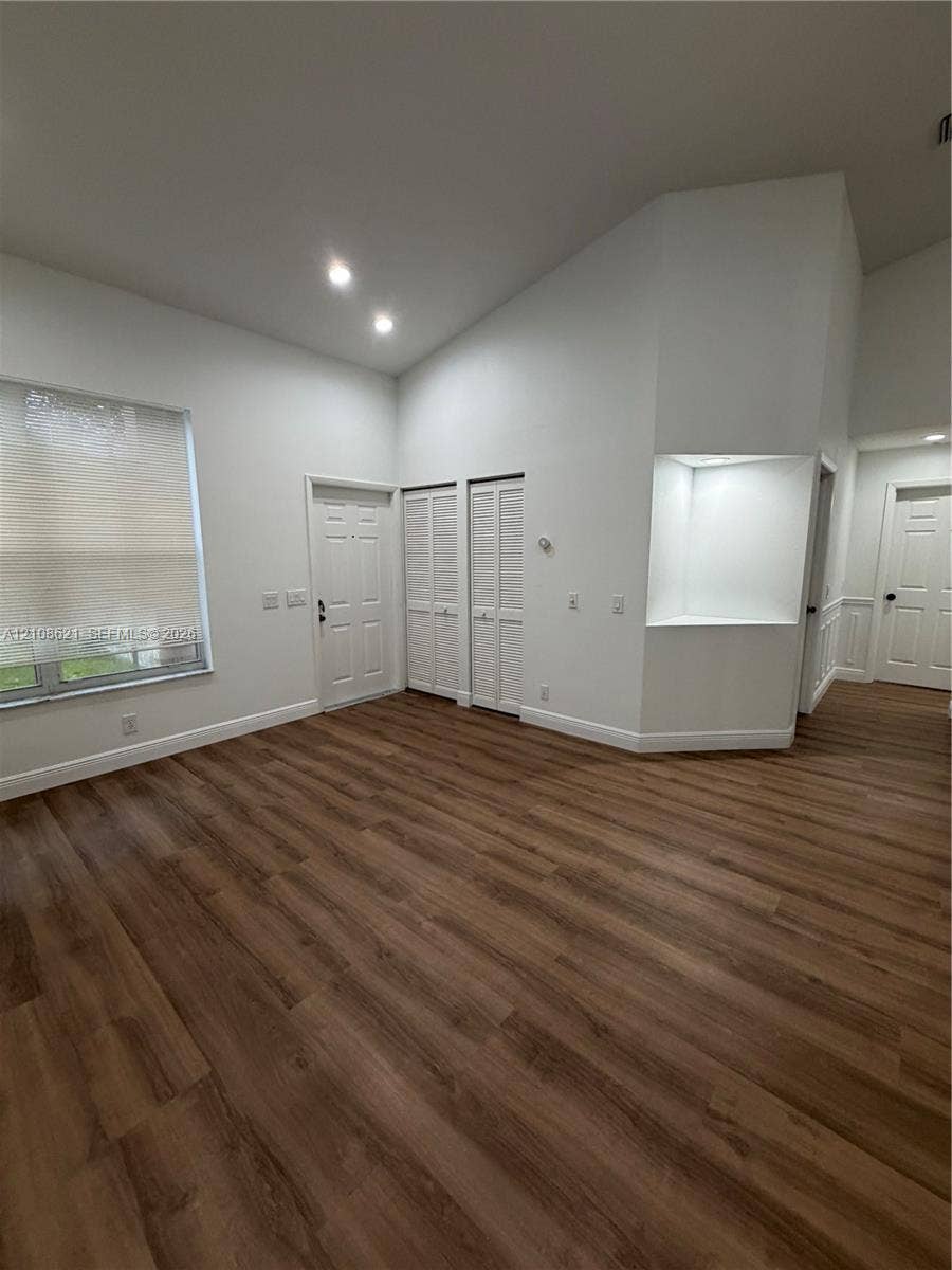 Vaulted ceilings, wood-finish flooring, recessed lighting, built-in recessed wall shelving, and louvered-panel closet doors