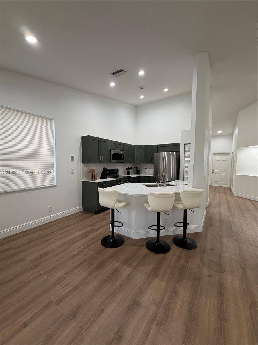 Kitchen featuring dark-toned cabinetry, light-toned countertops, wood-finish flooring, and recessed ceiling lighting