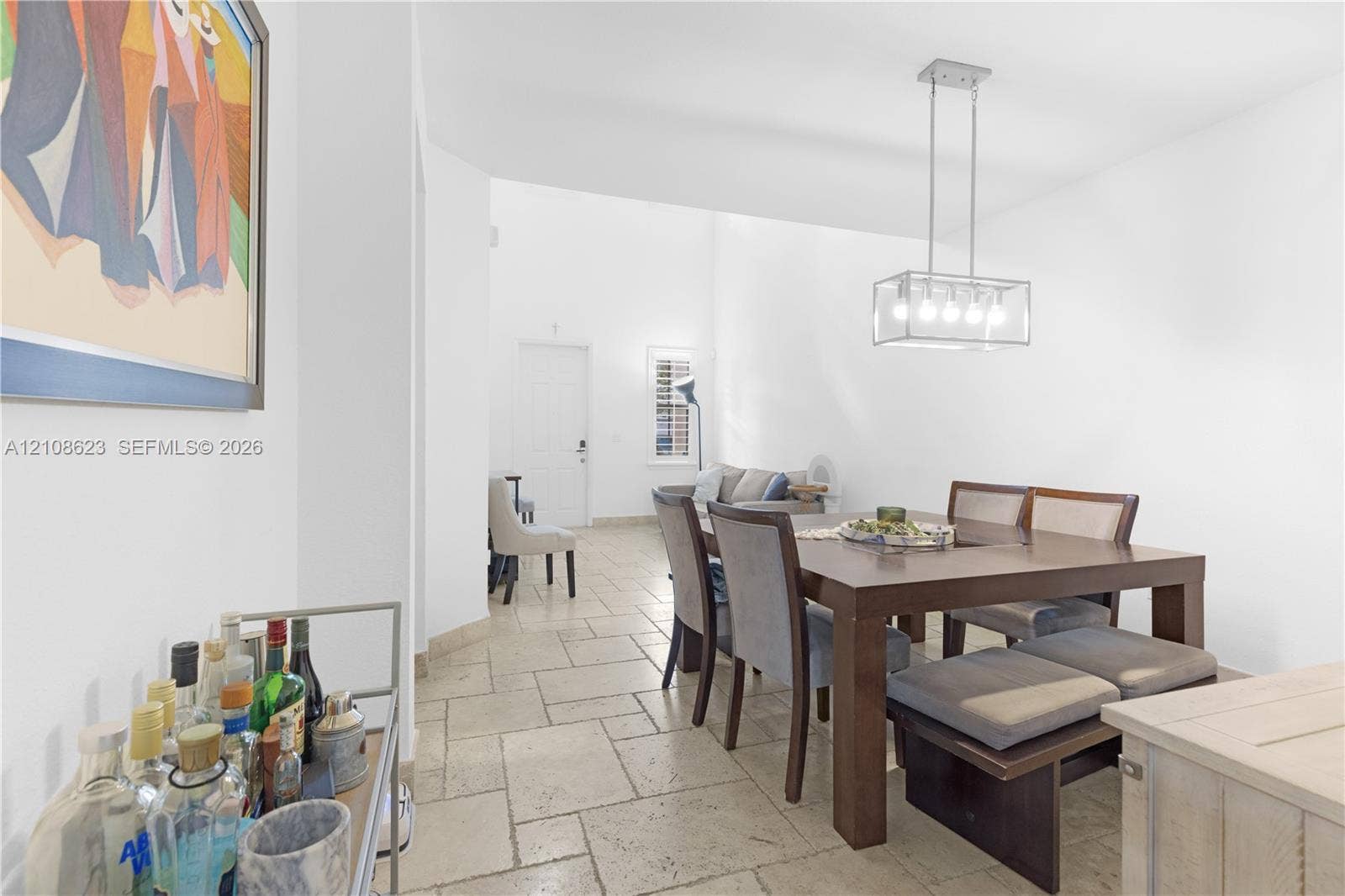 High-ceilinged interior space featuring light-toned stone-finish tile flooring and a rectangular, multi-light metal pendant fixture