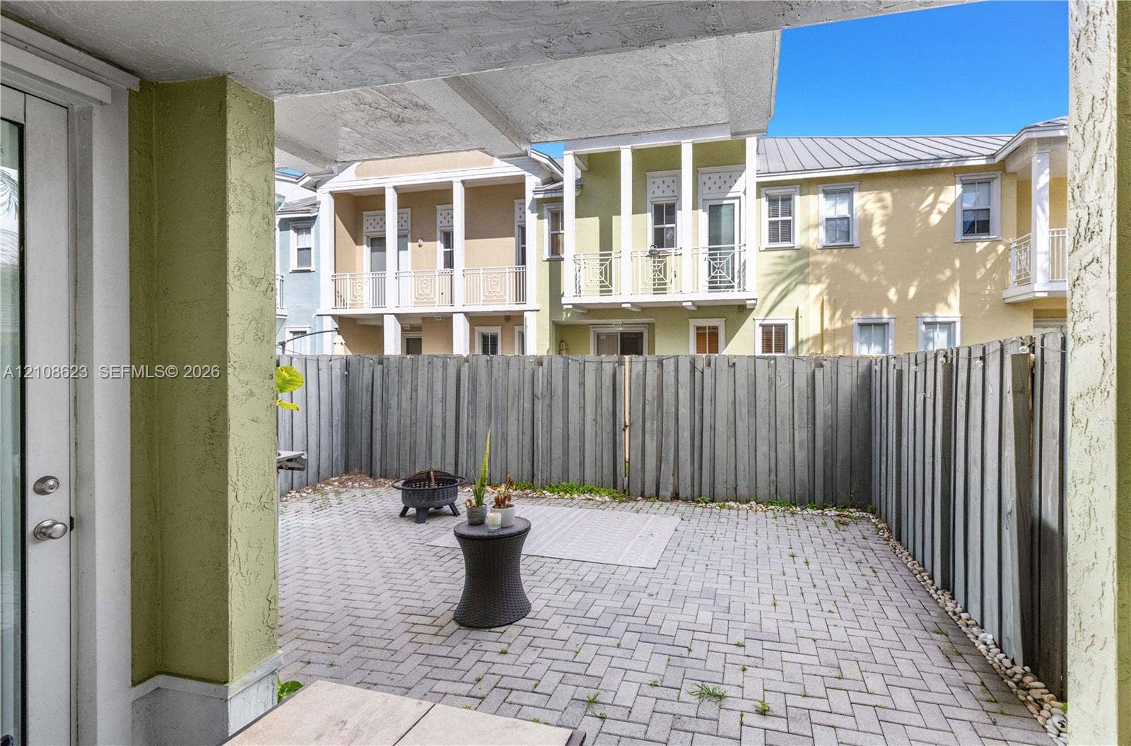 Private courtyard featuring herringbone-patterned paver flooring and full-height wood fencing