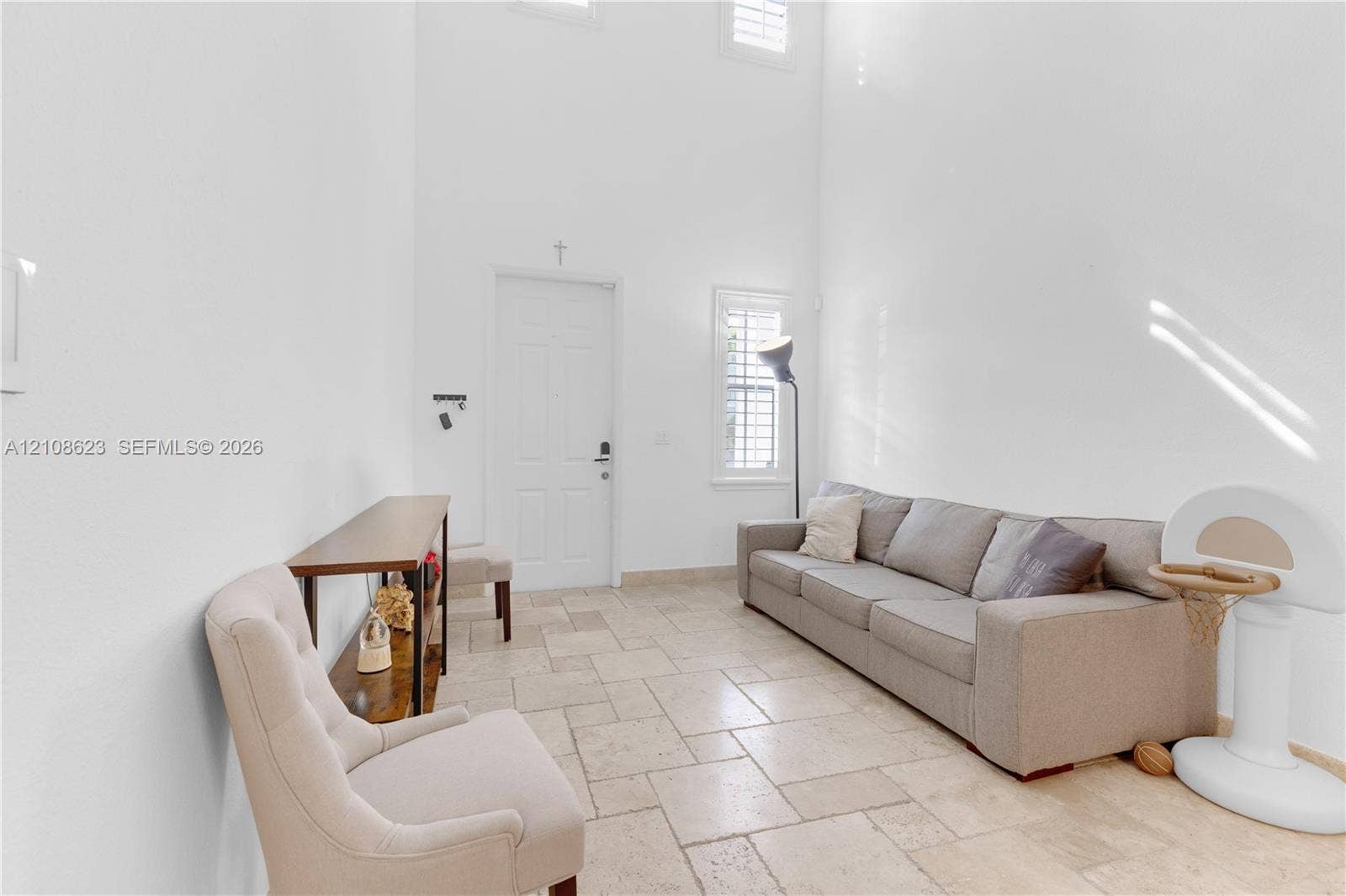 High-ceiling interior featuring tile flooring, multi-pane windows, and plantation shutters