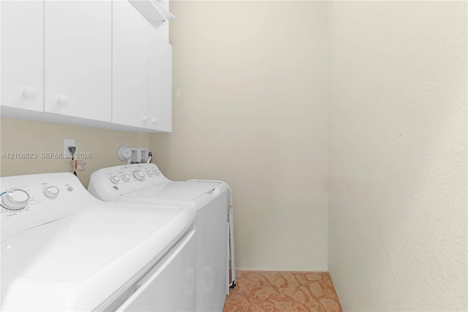 Laundry area featuring white shaker-style wall cabinetry and patterned flooring
