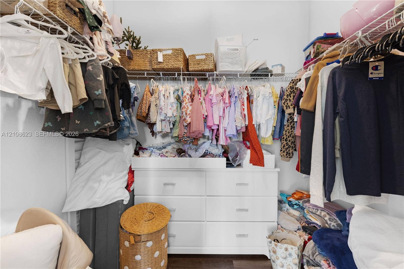 Walk-in closet featuring tiered wire shelving and integrated white six-drawer cabinetry