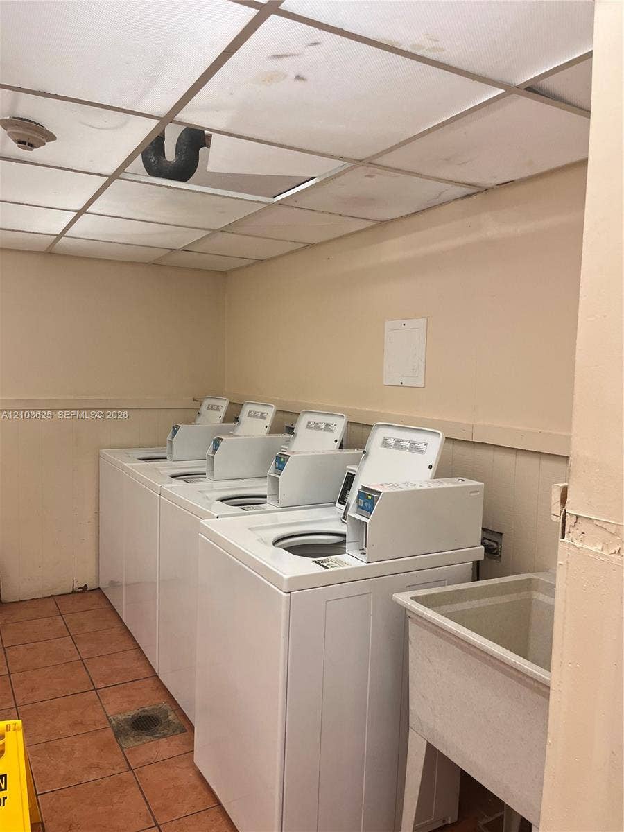 3650 Inverrary Drive, #1Q, Lauderhill, FL 33319 Laundry room featuring multiple top-load washers, a drop-in utility sink, and tile flooring