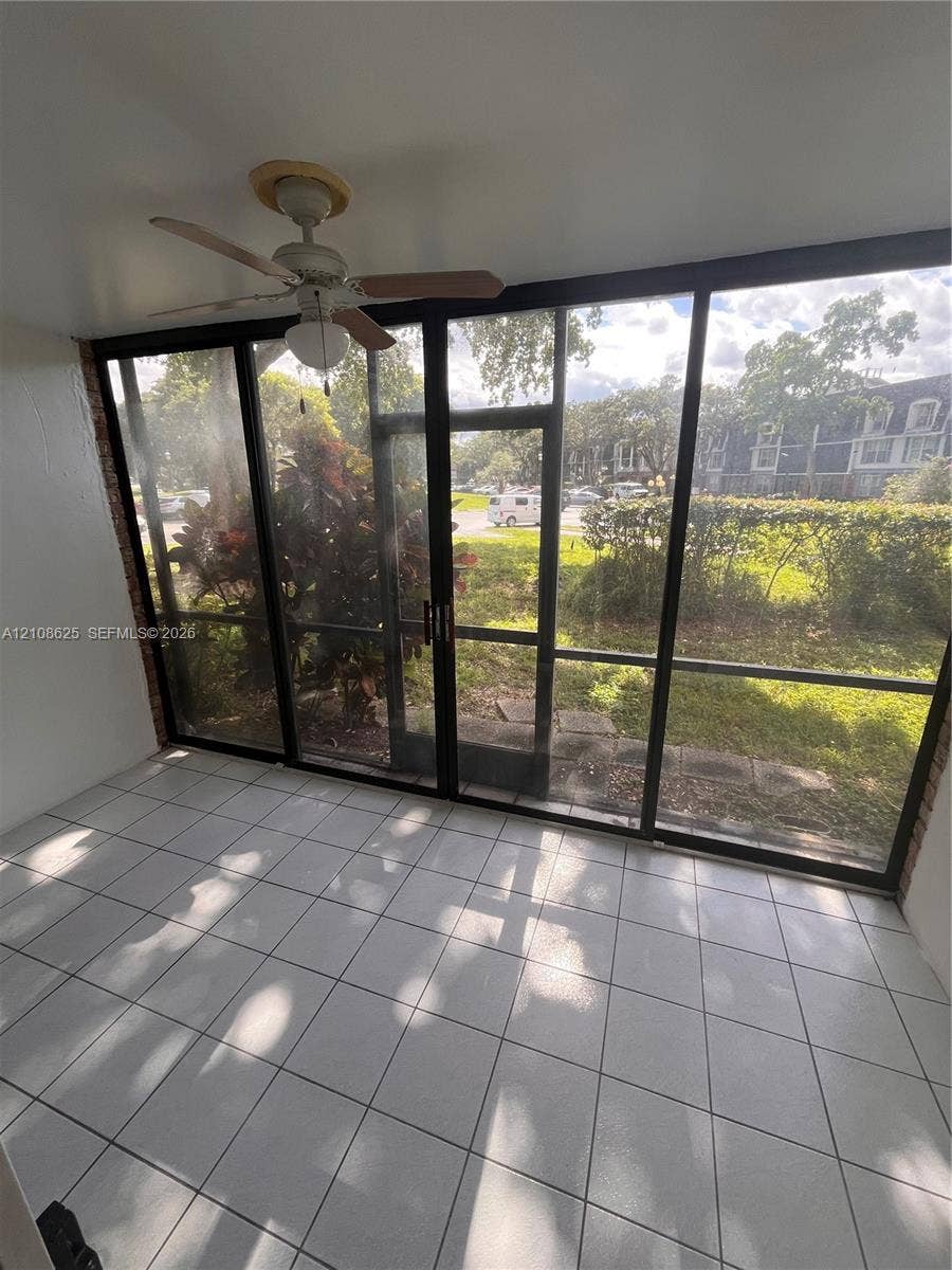 3650 Inverrary Drive, #1Q, Lauderhill, FL 33319 Enclosed sunroom featuring ceramic tile flooring, a ceiling fan with integrated lighting, and expansive floor-to-ceiling screen panels with sliding door access