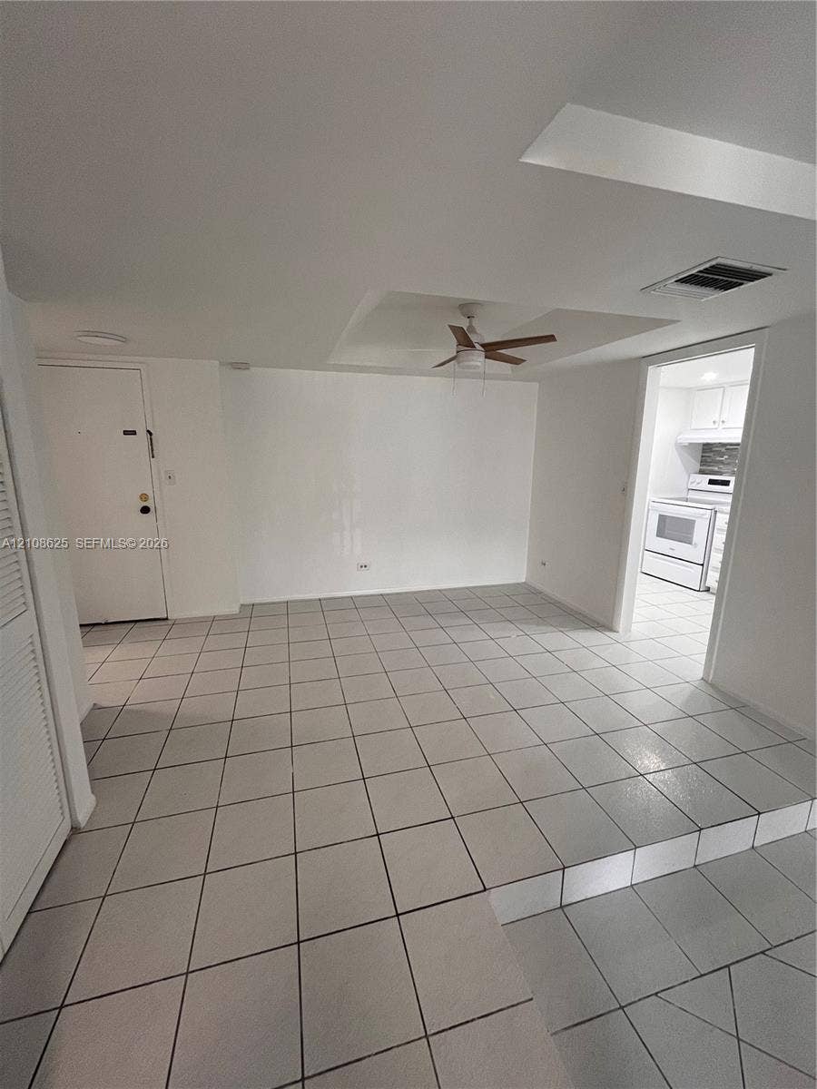 3650 Inverrary Drive, #1Q, Lauderhill, FL 33319 Interior space featuring a multi-level floor plan with ceramic tile flooring, a tray ceiling, and a central ceiling fan