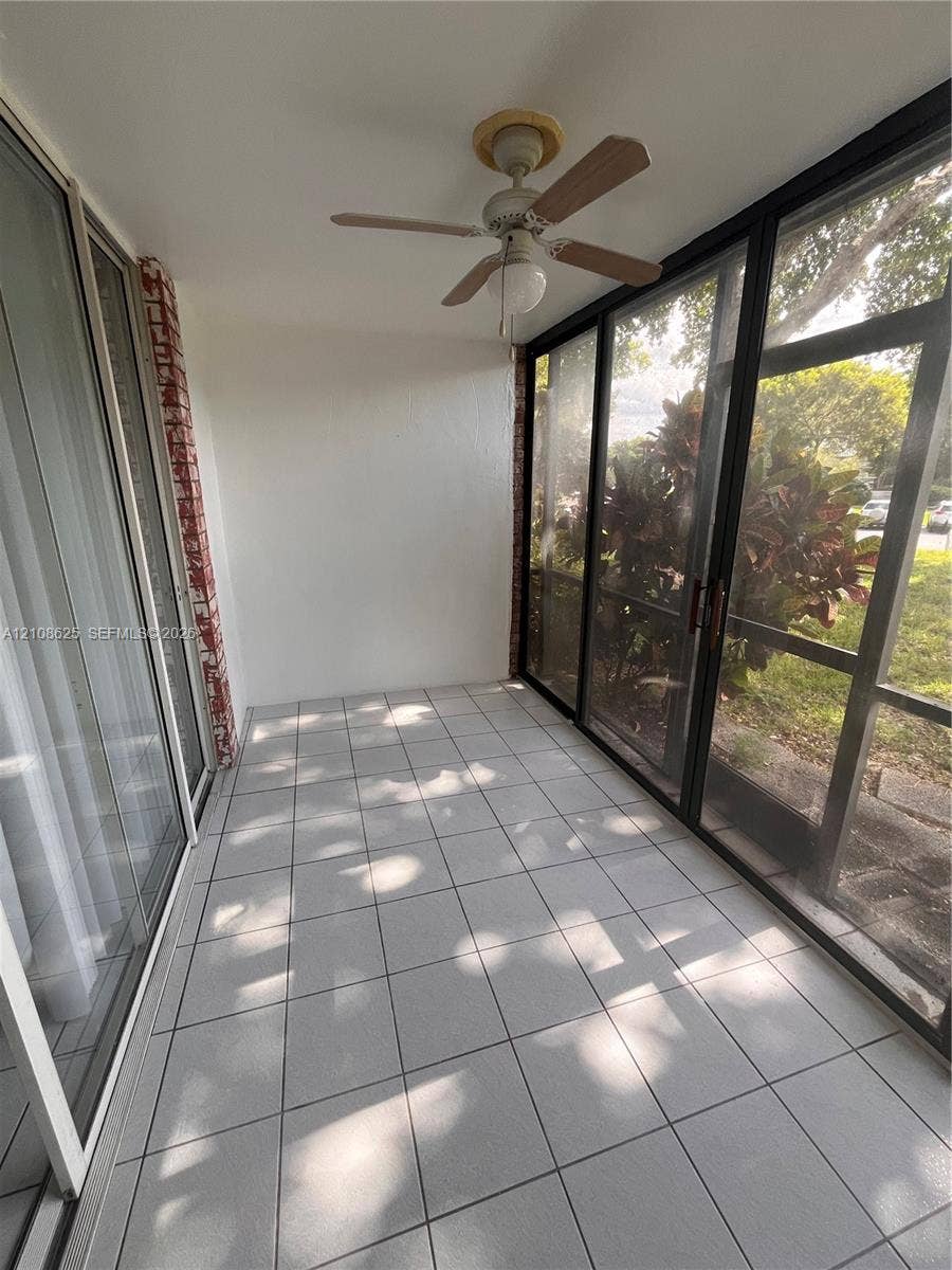 3650 Inverrary Drive, #1Q, Lauderhill, FL 33319 Enclosed patio featuring tile flooring, a ceiling fan with integrated light, floor-to-ceiling glass sliding doors, and a screened perimeter wall