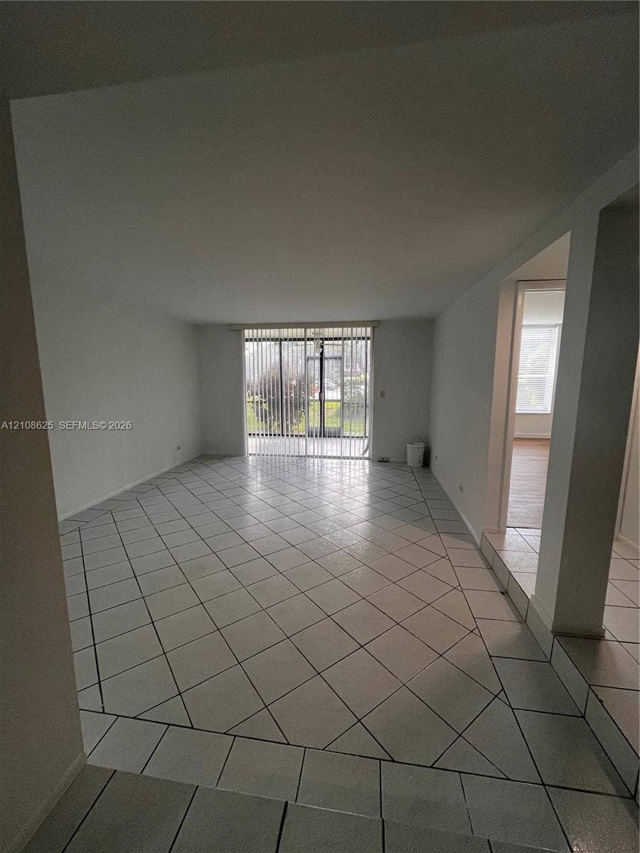 3650 Inverrary Drive, #1Q, Lauderhill, FL 33319 Open-concept interior featuring diagonal tile flooring and sliding glass doors with vertical blinds