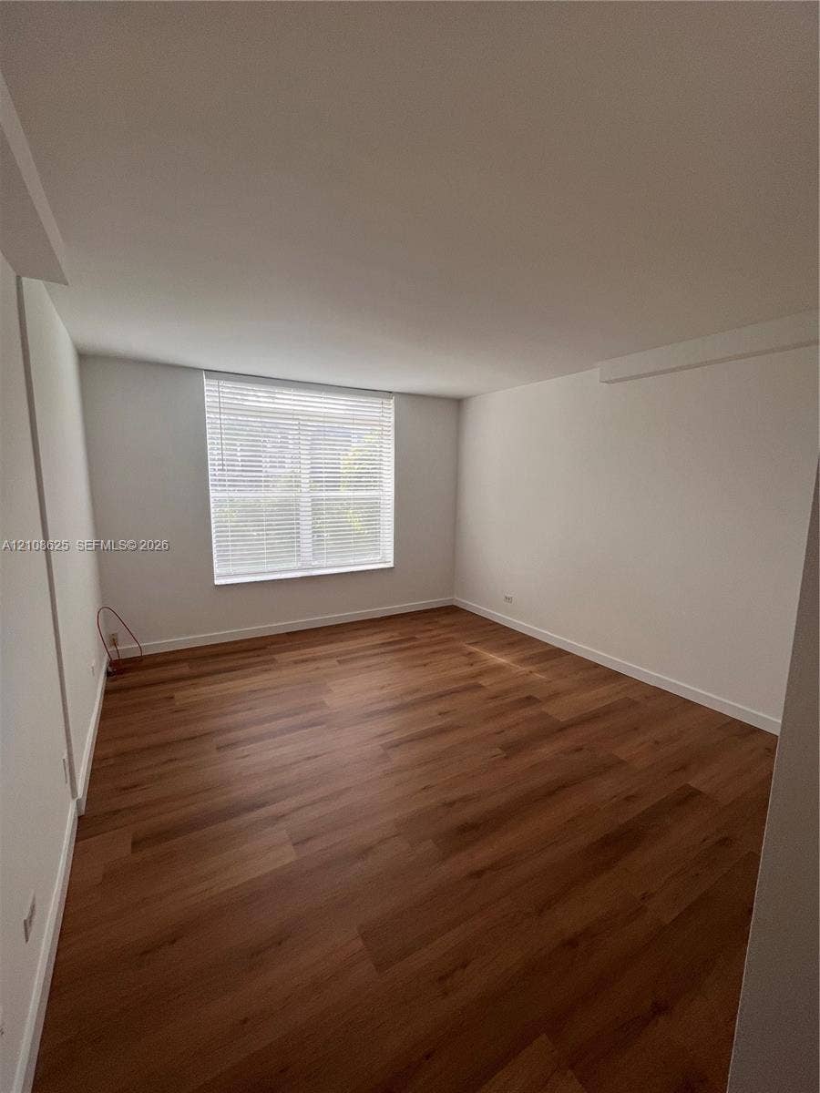 3650 Inverrary Drive, #1Q, Lauderhill, FL 33319 Interior room featuring wood-finish flooring, neutral walls, and a single window with installed horizontal blinds
