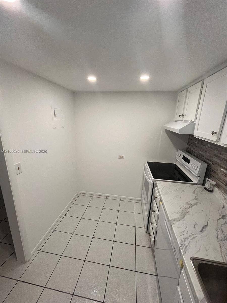 3650 Inverrary Drive, #1Q, Lauderhill, FL 33319 Kitchen featuring white cabinetry, stone-patterned countertops, recessed lighting, tile flooring, and a decorative backsplash