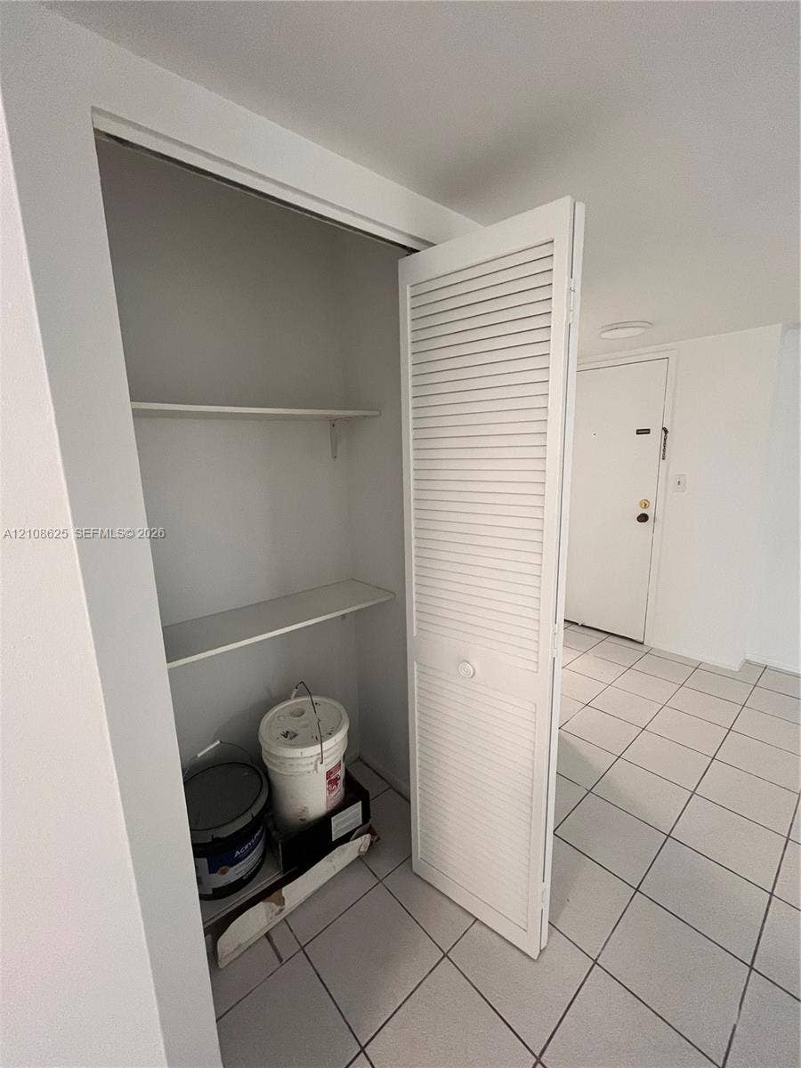 3650 Inverrary Drive, #1Q, Lauderhill, FL 33319 Storage closet featuring louvered bi-fold doors and interior shelving, set above white tiled flooring