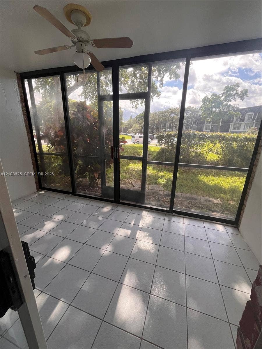 3650 Inverrary Drive, #1Q, Lauderhill, FL 33319 Enclosed patio featuring white tile flooring, expansive floor-to-ceiling screens, and a ceiling-mounted fan