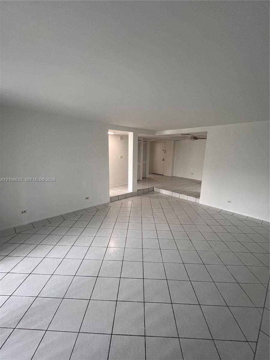3650 Inverrary Drive, #1Q, Lauderhill, FL 33319 Open interior space featuring neutral ceramic tile flooring and multi-level floor plan with recessed structural partitions