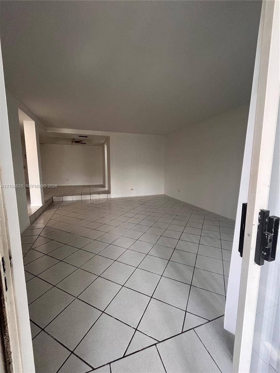 3650 Inverrary Drive, #1Q, Lauderhill, FL 33319 Interior space featuring neutral wall tones, large-format diagonal tile flooring, and a multi-level floor plan with an elevated platform