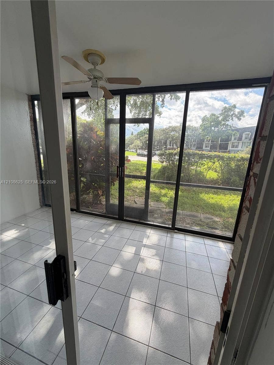 3650 Inverrary Drive, #1Q, Lauderhill, FL 33319 Enclosed patio featuring white tile flooring, ceiling fan with integrated lighting, and expansive screened panels
