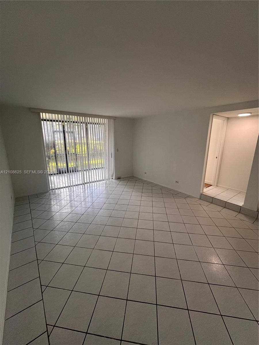 3650 Inverrary Drive, #1Q, Lauderhill, FL 33319 Open interior featuring large-format diagonal tile flooring, sliding glass patio doors with vertical blinds, and recessed ceiling lighting