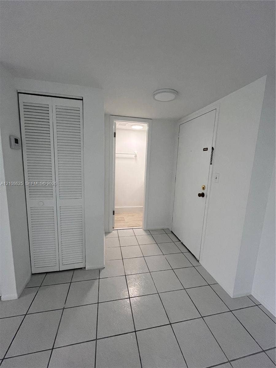 3650 Inverrary Drive, #1Q, Lauderhill, FL 33319 Foyer featuring neutral tile flooring, louvered bi-fold closet doors, and a flush-mount ceiling light