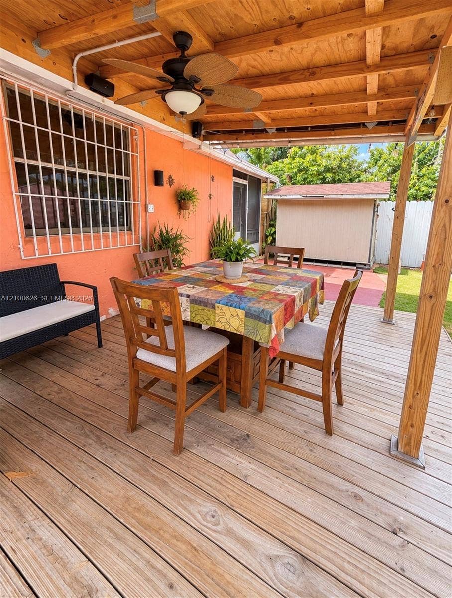 971 NE 156th Terrace, North Miami Beach, FL 33162 Covered outdoor deck featuring wood-plank flooring, an exposed wood-beam ceiling, and a ceiling-mounted fan with integrated light fixture
