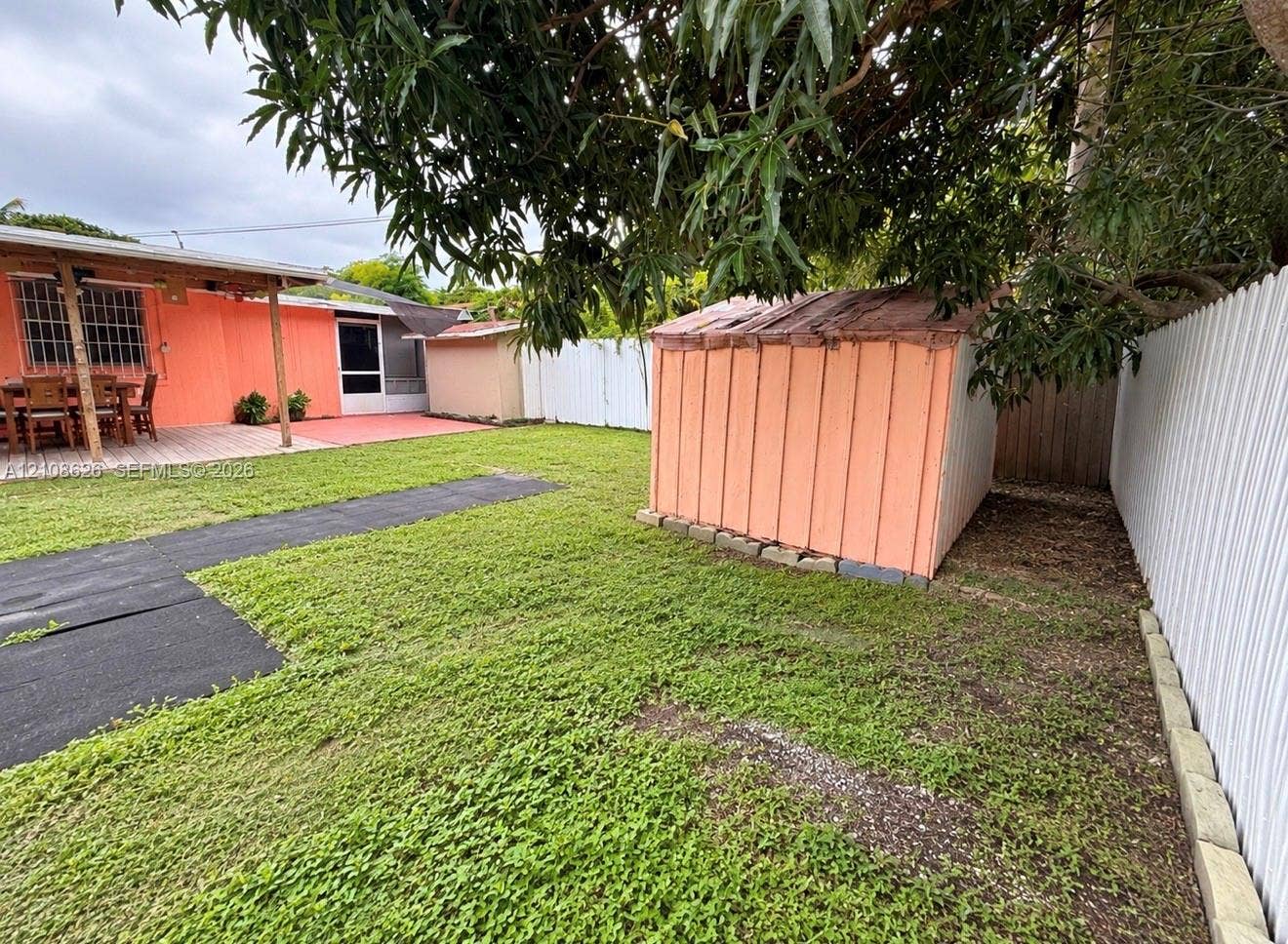 971 NE 156th Terrace, North Miami Beach, FL 33162 Backyard featuring a grass lawn, a detached storage structure, a paved patio, and perimeter fencing