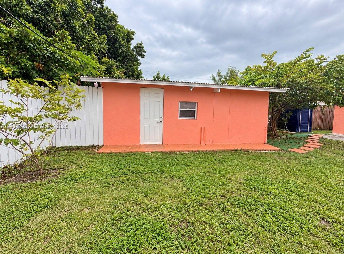 971 NE 156th Terrace, North Miami Beach, FL 33162 Detached structure featuring a stucco exterior, single-entry door, corrugated metal roofing, and a white privacy fence