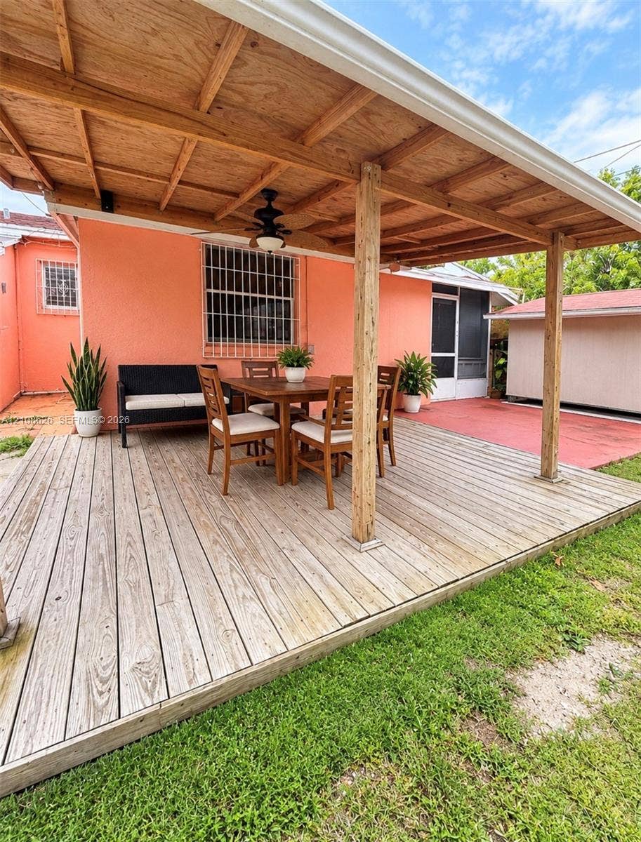 971 NE 156th Terrace, North Miami Beach, FL 33162 Covered wood deck featuring a ceiling-mounted fan, wood-beam supports, and metal security bars on exterior windows