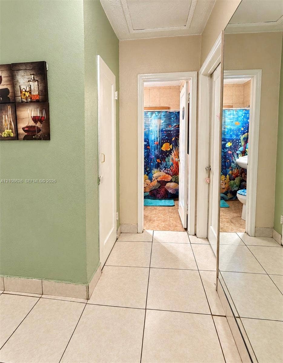 971 NE 156th Terrace, North Miami Beach, FL 33162 Hallway featuring large-format ceramic tile flooring, full-length wall mirror, and solid-core interior doors