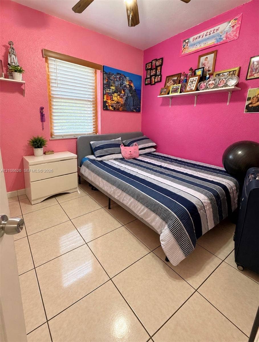 971 NE 156th Terrace, North Miami Beach, FL 33162 Ceramic tile flooring, horizontal slat window blinds, ceiling fan, and wall-mounted shelving