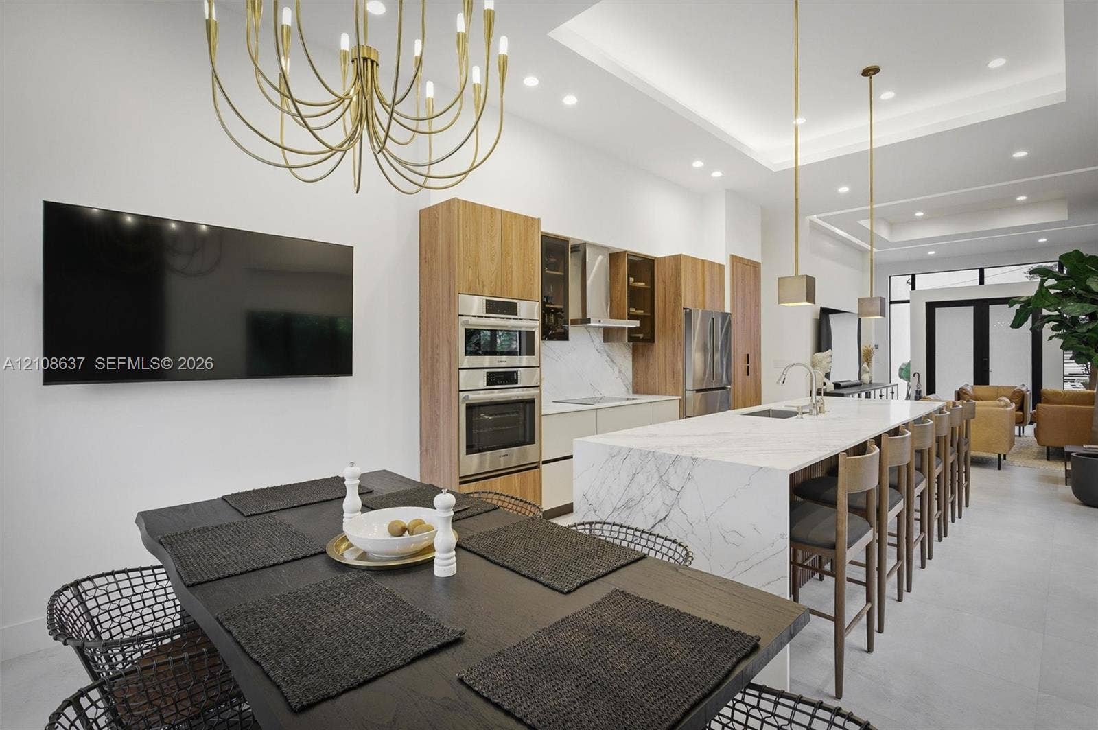 22900 SW 122nd Place, Miami, FL 33170 Open-concept kitchen featuring an expansive center island with stone-finish waterfall countertop, integrated stainless steel appliances, flat-panel cabinetry, tray ceiling with recessed lighting, and contemporary metal light fixtures