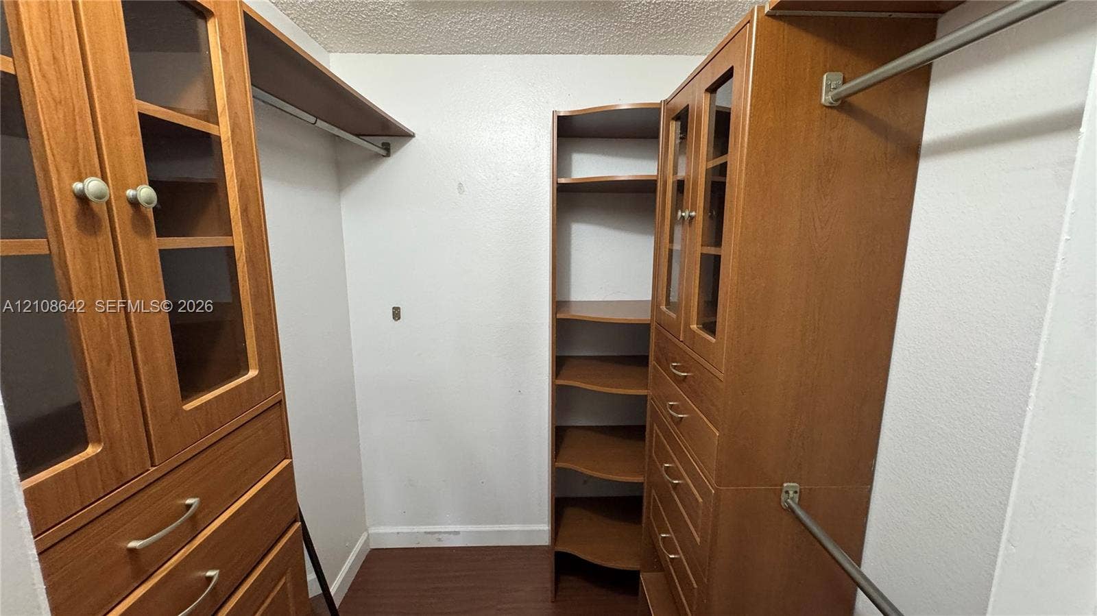 15661 SW 104th Terrace, #3212, Miami, Miami, FL 33196 Walk-in closet featuring built-in wood-finish cabinetry, glass-paneled cabinet doors, integrated shelving, and metal hanging rods