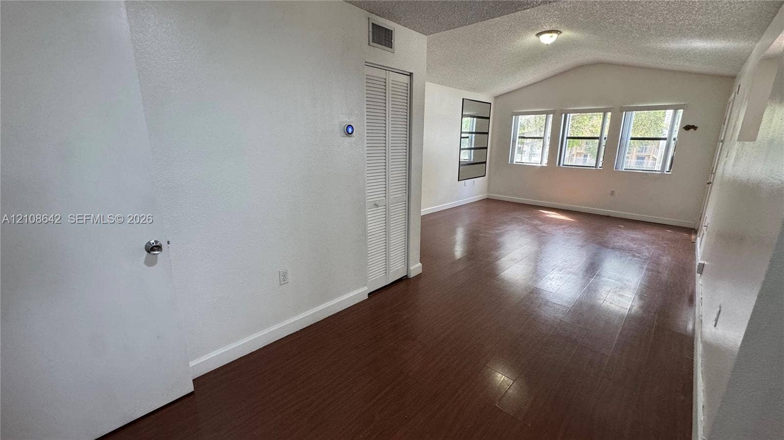 15661 SW 104th Terrace, #3212, Miami, Miami, FL 33196 Open living area featuring wood-finish flooring, vaulted ceilings, multiple windows providing natural light, and a bi-fold closet
