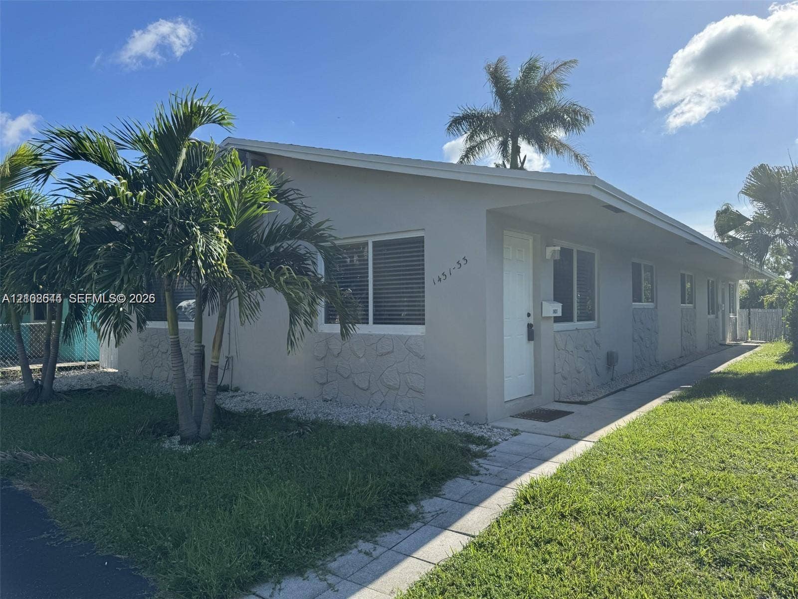 1431 N 14th Way, #rear, Hollywood, Hollywood, FL 33020 Single-story exterior featuring light-toned stucco walls, horizontal sliding windows, stone-veneer accents, and a paved walkway