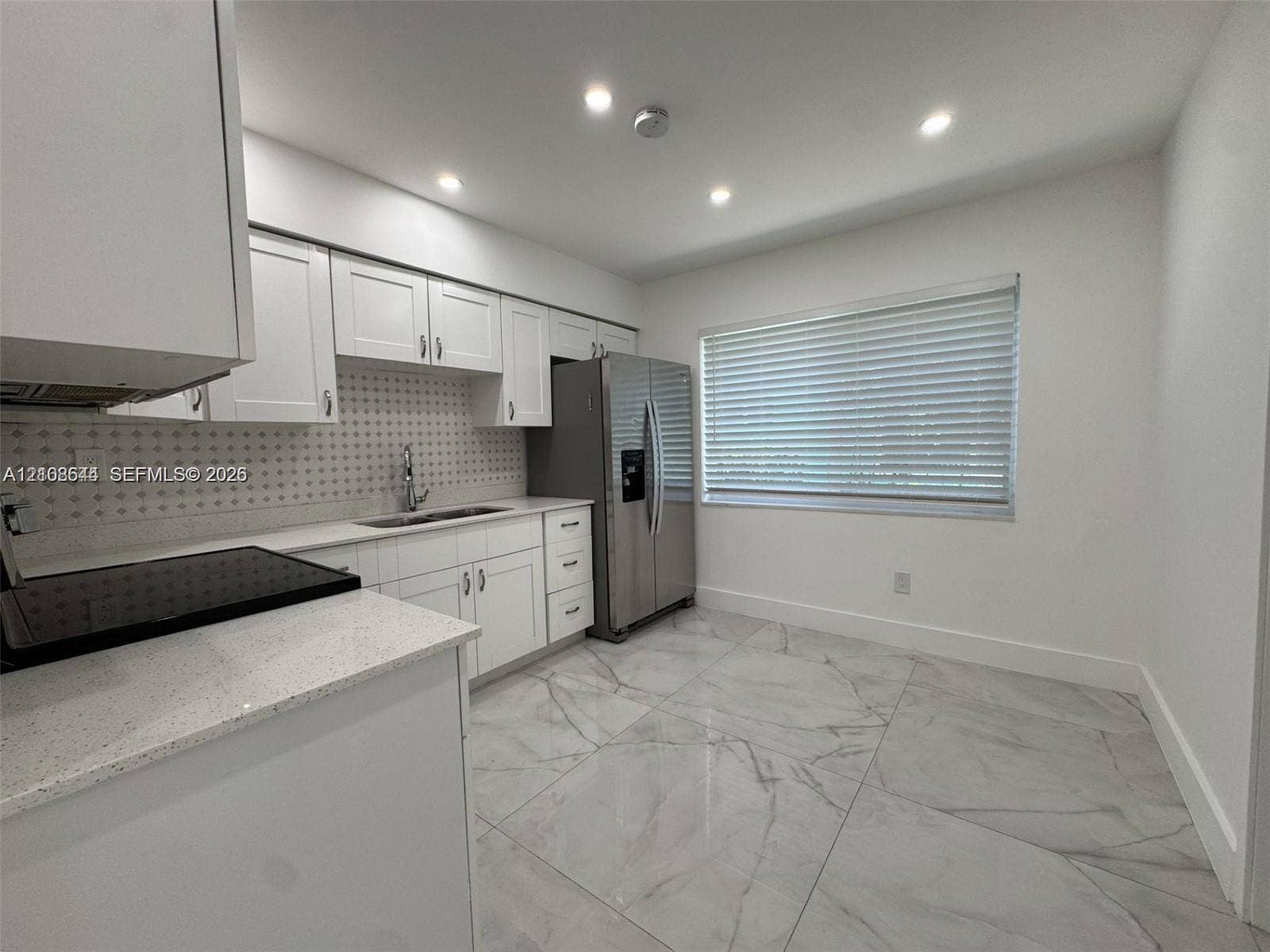 1431 N 14th Way, #rear, Hollywood, Hollywood, FL 33020 Kitchen featuring white cabinetry, quartz countertops, a patterned tile backsplash, large-format polished tile flooring, and stainless steel refrigerator