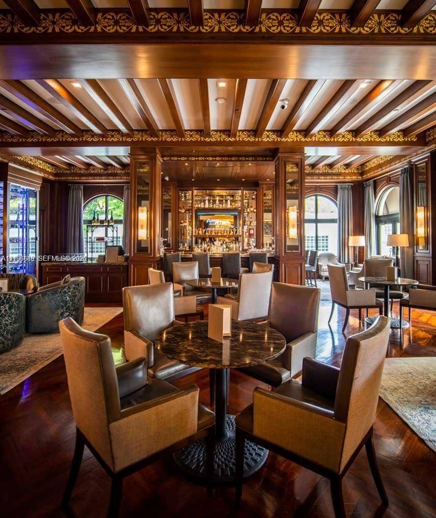 20165 NE 39 Place, #403, Aventura, FL 33180 Ornate wood-paneled lounge featuring an intricate coffered ceiling with gold-leaf detailing, polished wood-finish flooring, built-in bar cabinetry, and arched windows
