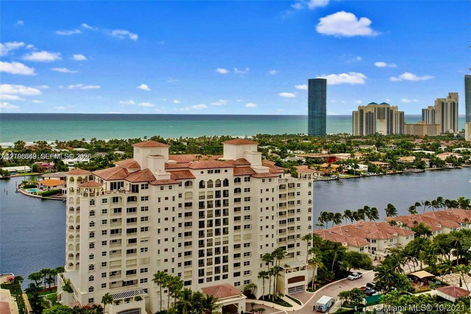 20165 NE 39 Place, #403, Aventura, FL 33180 High-rise multi-story building featuring a red tile roof and arched architectural detailing, situated on a waterfront lot with canal access and coastal exposure