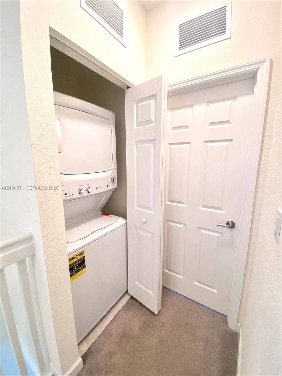 3288 W 106th Terrace, #3288, Hialeah, Hialeah, FL 33018 Stackable laundry appliance set housed in a recessed closet with a paneled door, featuring neutral wall finishes and carpeted flooring