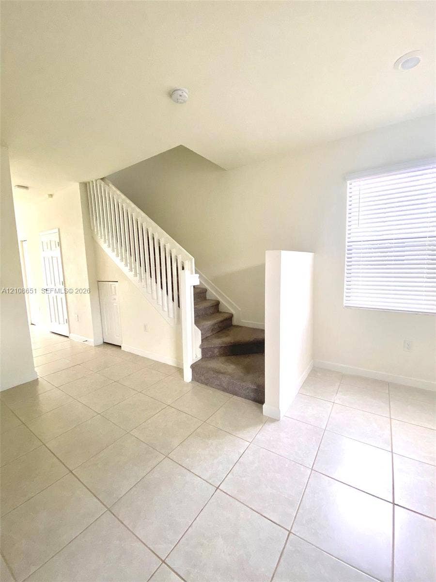 3288 W 106th Terrace, #3288, Hialeah, Hialeah, FL 33018 Staircase featuring a white balustrade, carpeted steps, and large-format tile flooring
